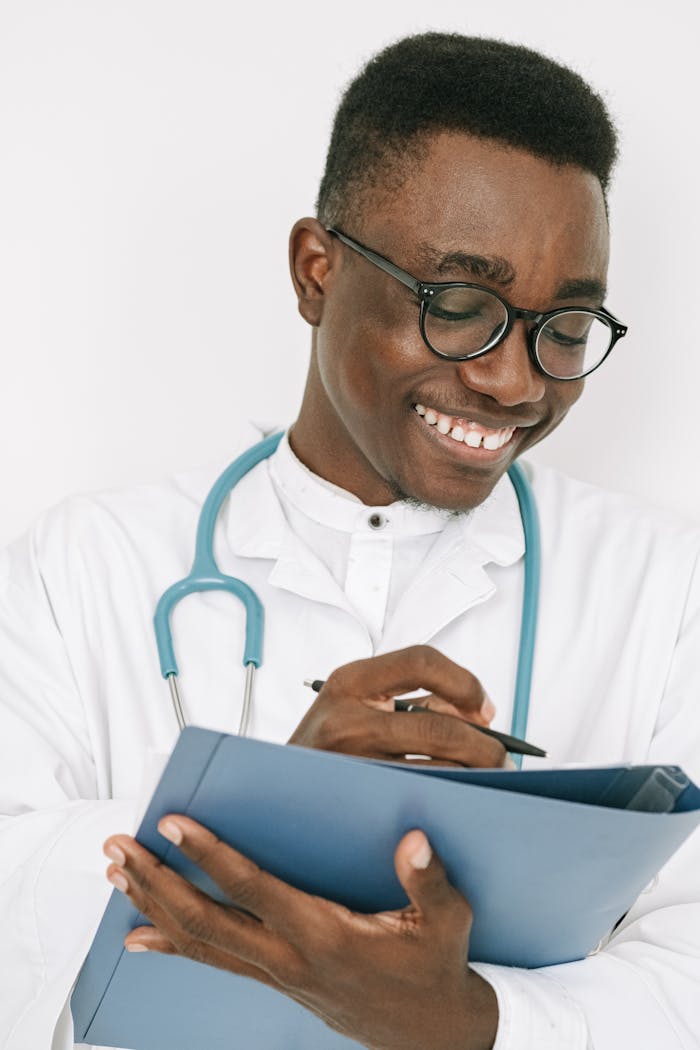 Friendly doctor with stethoscope writing on a chart in a bright room.