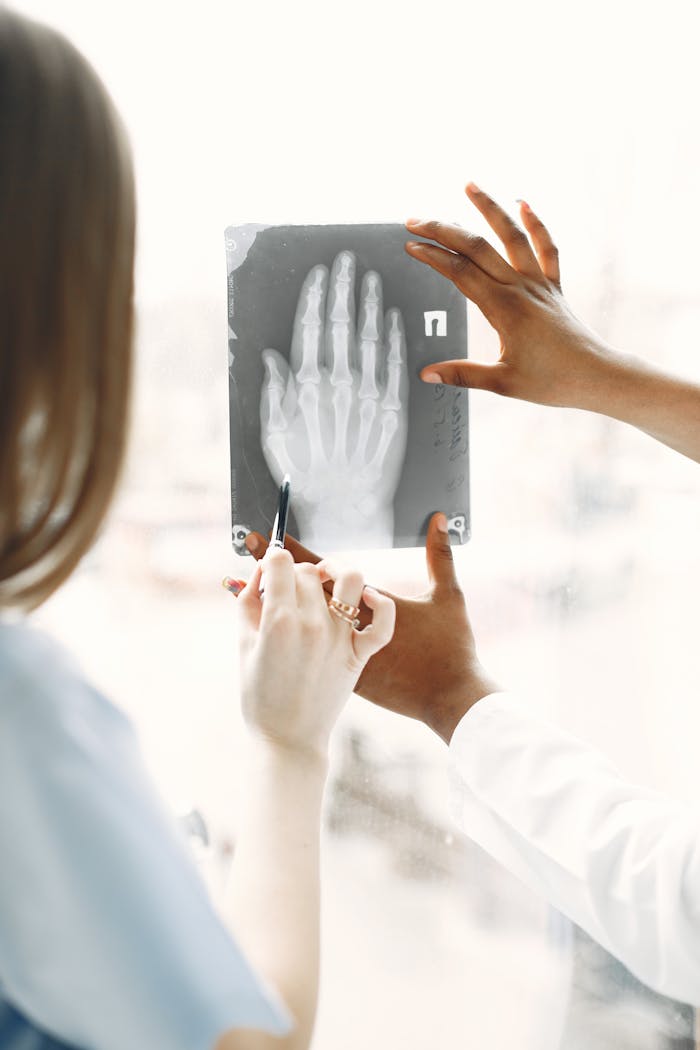 Medical professionals analyzing an X-ray image of a hand in a clinical setting.